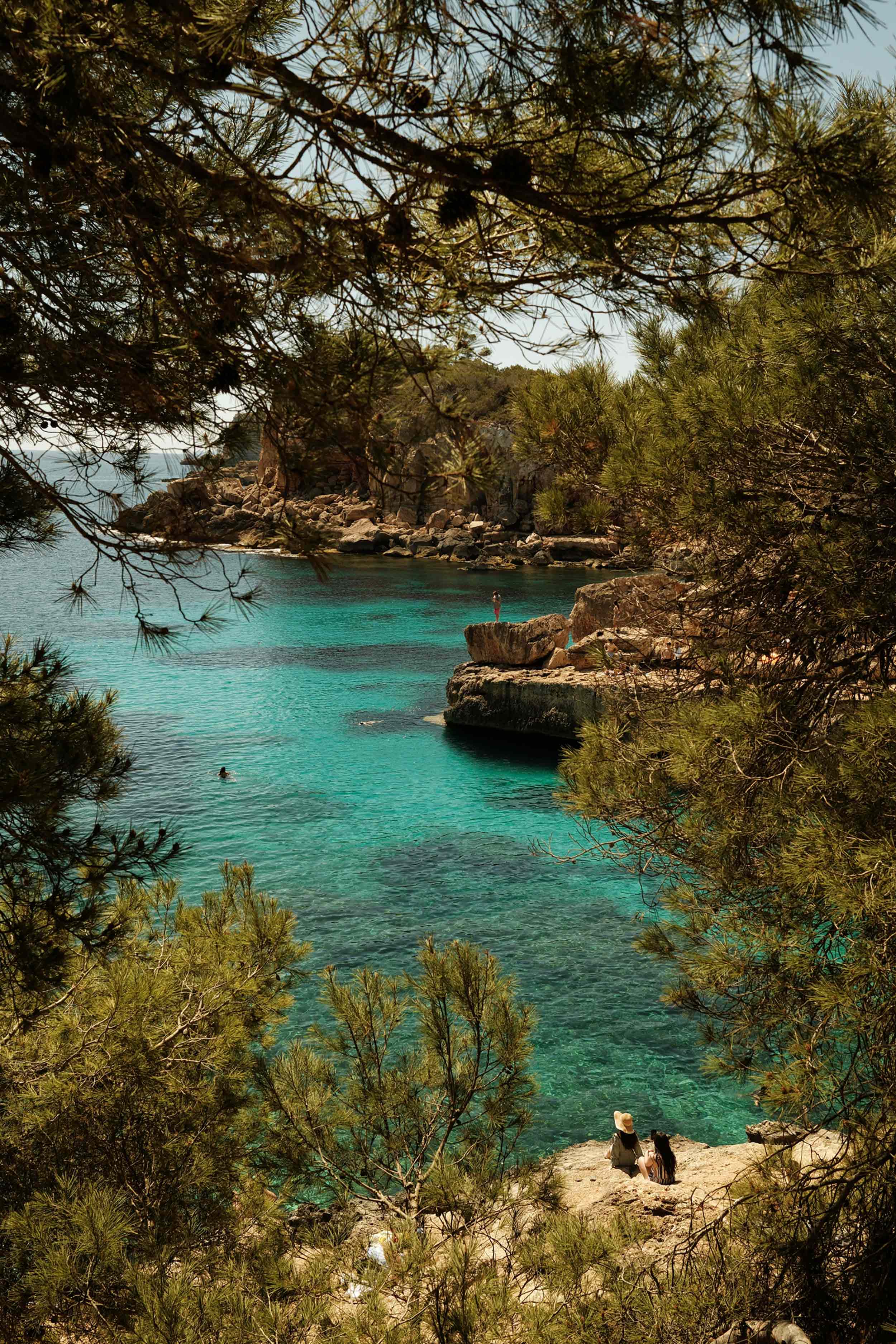 Quiet beauty by the sea. Two women pause above a turquoise cove, where clear water meets wild green. A tranquil moment that captures the essence of Crete — nature, connection, and calm discovery.